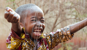 young African boy smiling in the rain